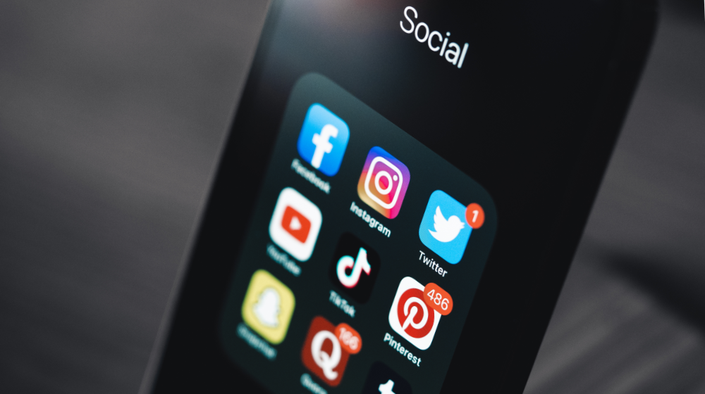 Smartphone mit einem Ordner mit verschiedenen Sozialen Medien abgebildet