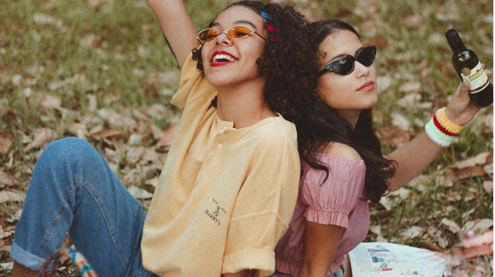 Zwei Frauen die genüsslich ein Bier auf einer Wiese verzerren