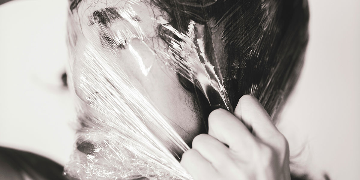 Frau zerreißt Plastikfolie über ihrem Gesicht in schwarz-weiß. Depressionen - unsichtbar